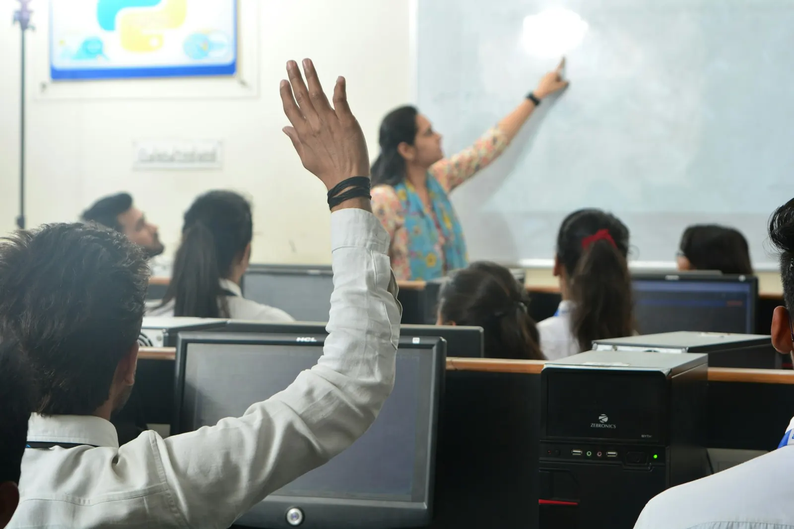 A D-TECH classroom: a student raises a hand while the trainer explains at the whiteboard